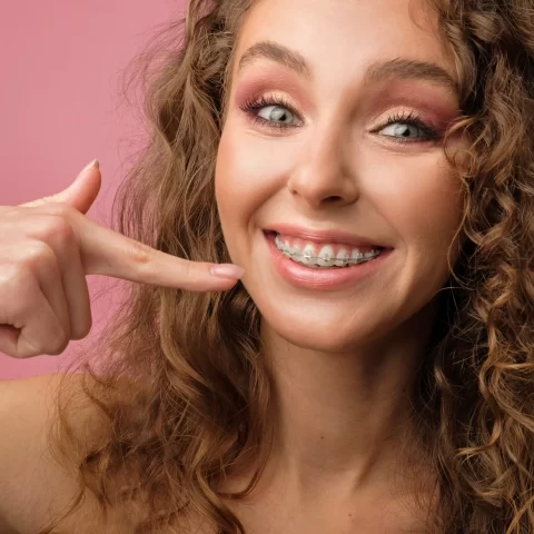 Girl confidently showing her clear braces with a bright smile.